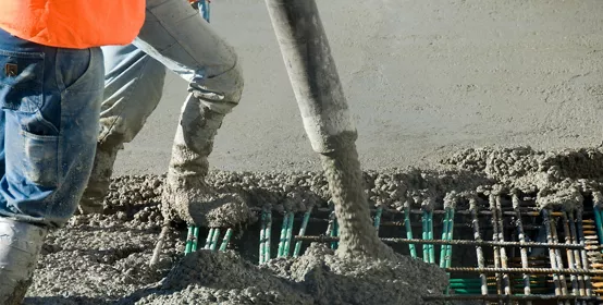 Two men guide cement into place, visible from the waist down.