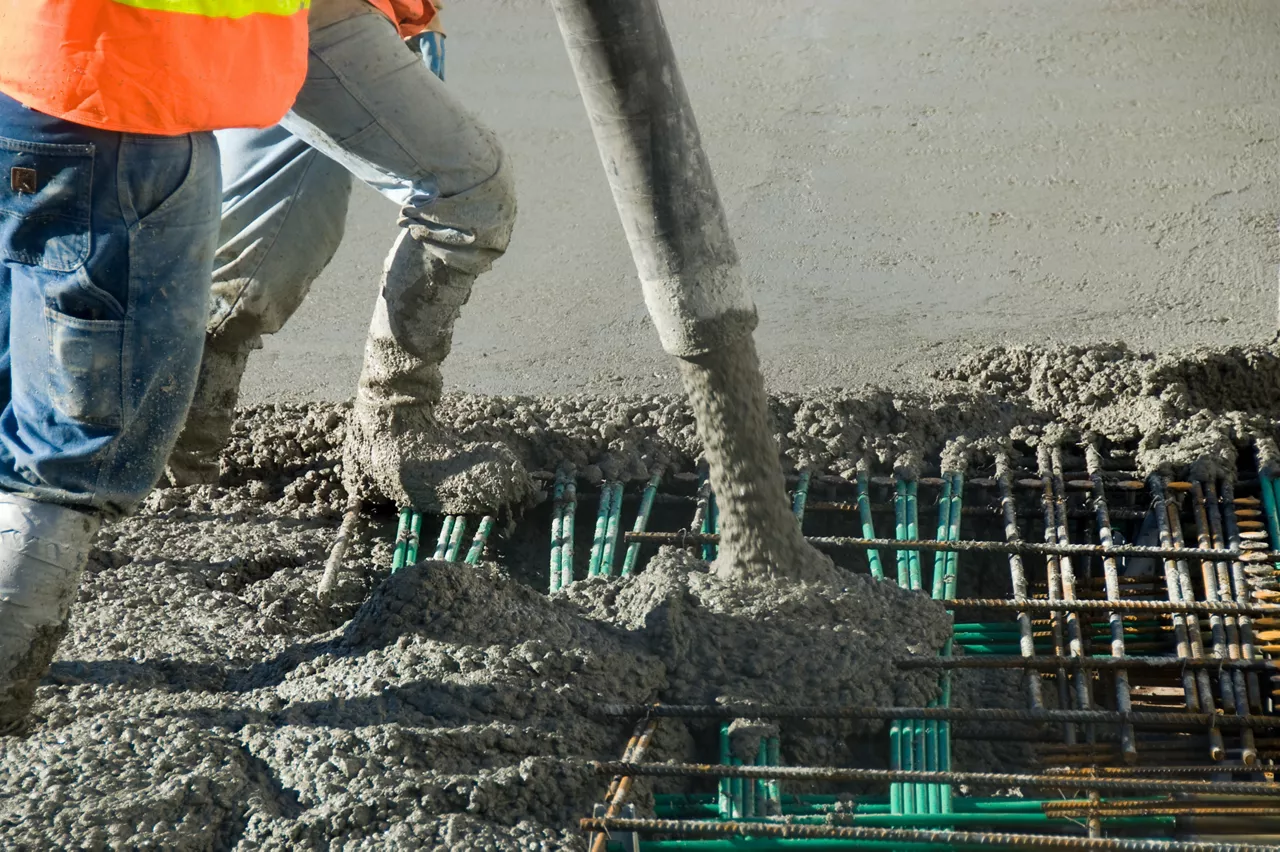 Two men guide cement into place