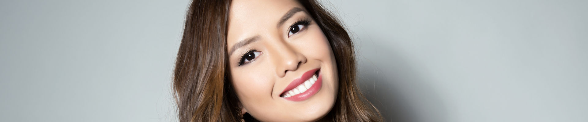 Retrato de joven y bella mujer asiática con piel clara con maquillaje sobre un fondo gris 