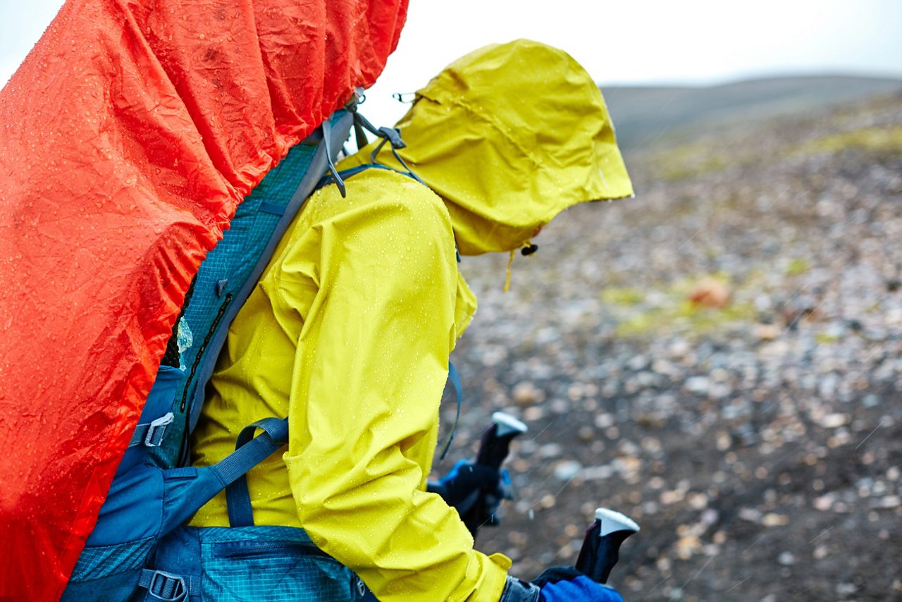 woman hiker on the trail in the Islandic mountains. Trek in National Park Landmannalaugar, Iceland. woman walking in the rain with a backpack in a raincoat and wearing a waterproof jacket