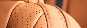 Part of beige leather car seat with the unfocused car interior on the background