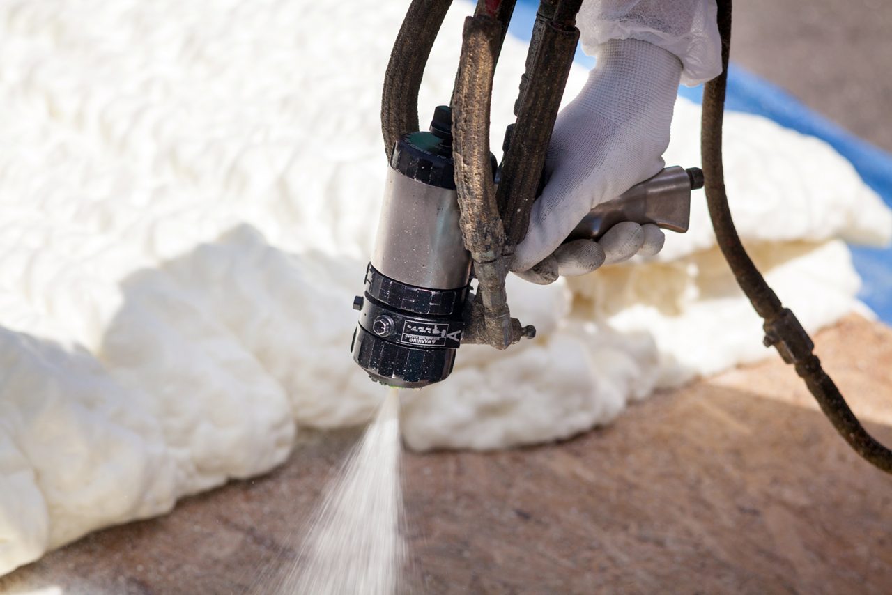 Person in protective white suit and respirator applies