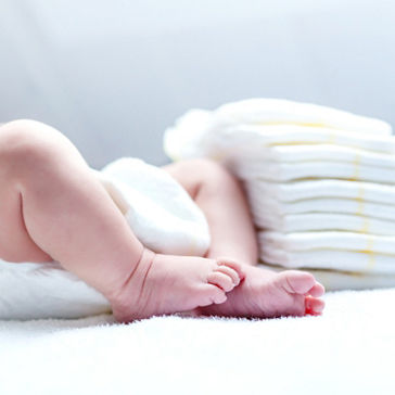 쌓여있는 기저귀들 옆에 기저귀를 착용하고 누워있는 아기