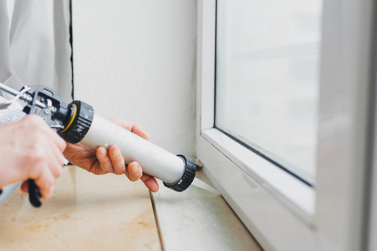 Worker applies silicone sealant to window 