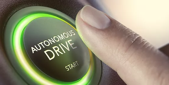 Finger pressing a push button to start a self-driving car. Composite image between a hand photography and a 3D background.