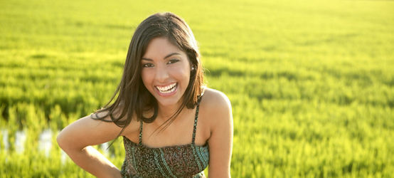 緑の田んぼの草原にいる美しいブルネットのインド人若い女性