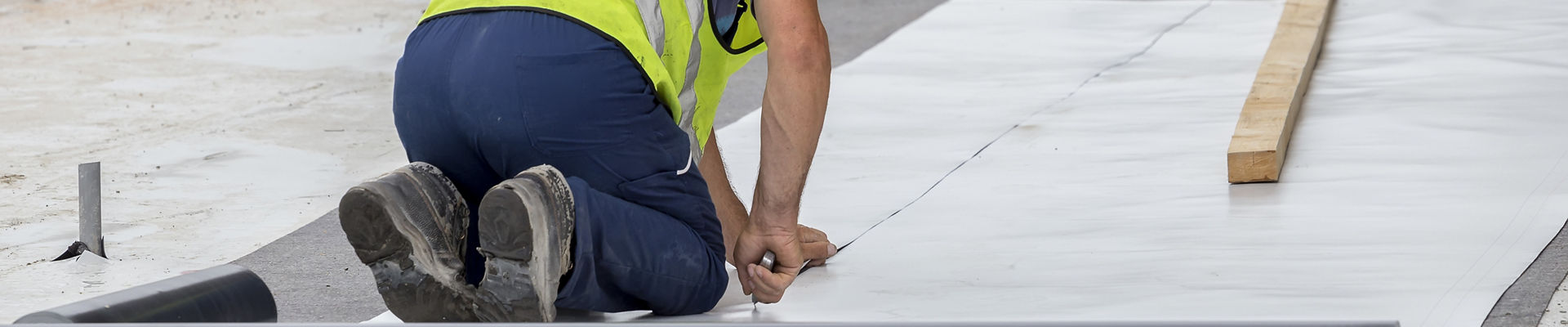 Construction worker installing roofing membrane