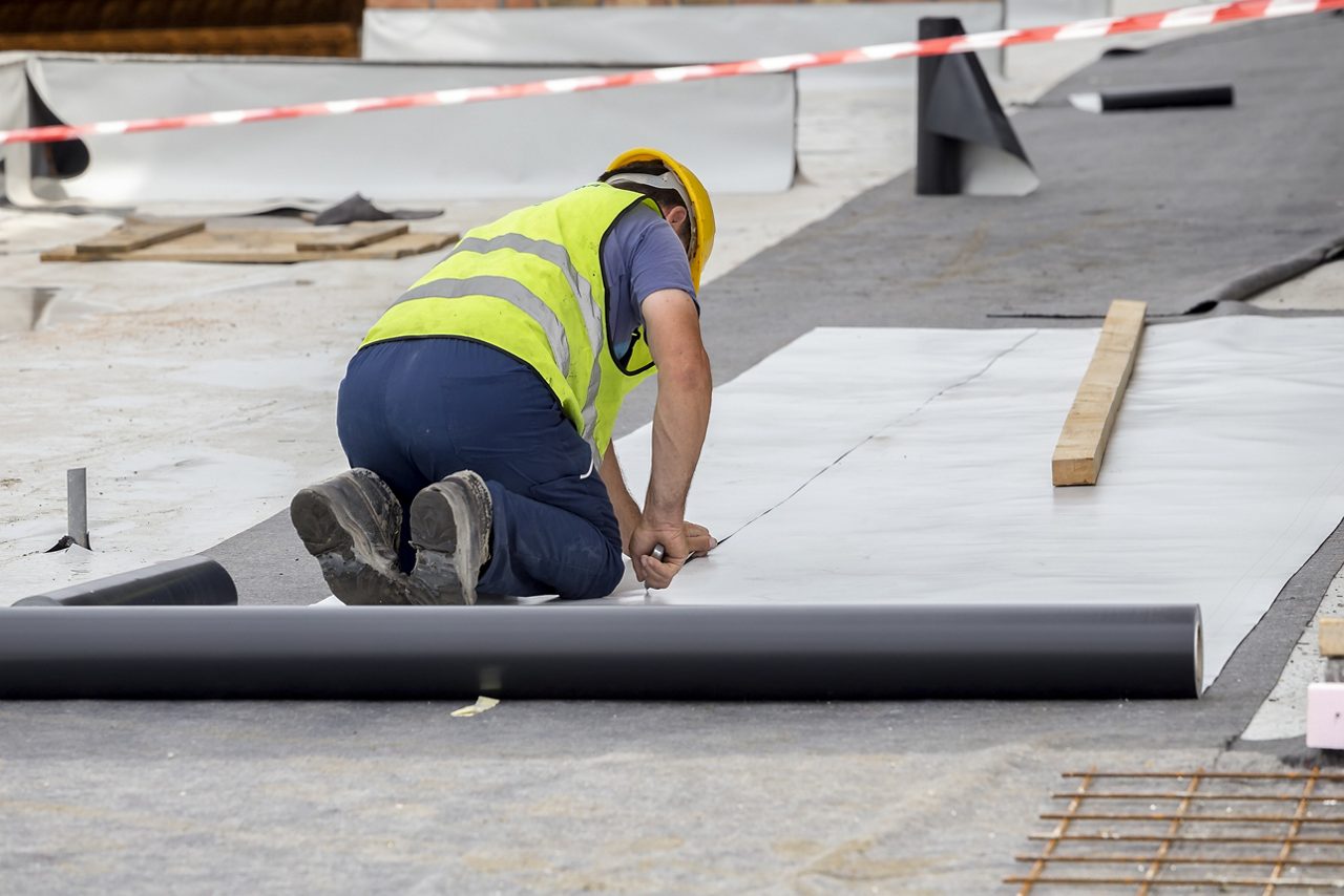 Construction worker installing roofing membrane