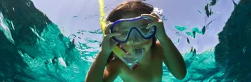 View from below photograph of a young boy wearing goggles while swimming