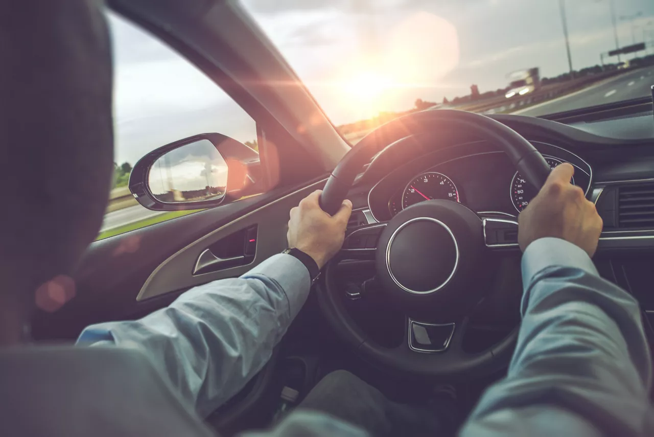 Man behind the wheel of a car looking out the front window 