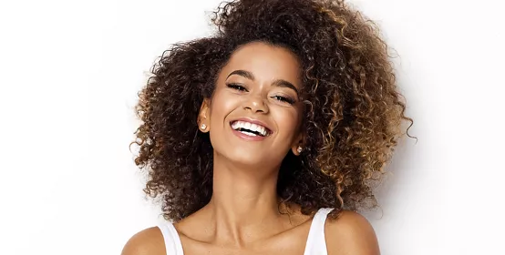 Beautiful African American girl with an afro hairstyle smiling on a white background.