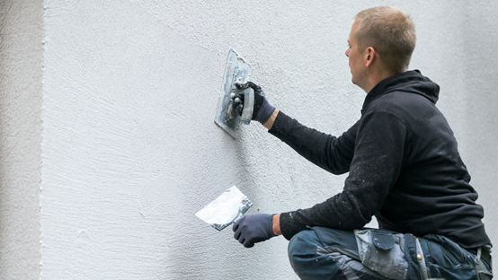 Person applying drymix to white wall