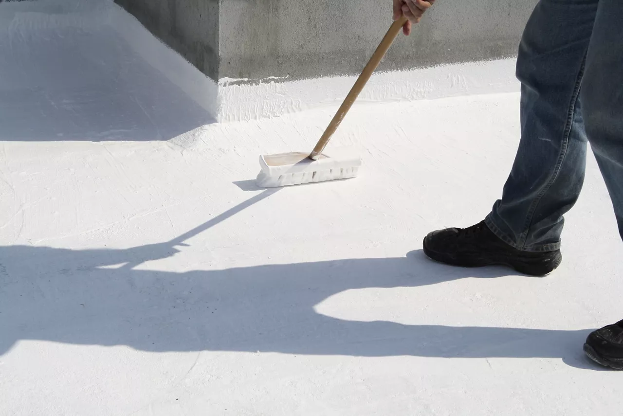 Person applying roof coating with a brush.