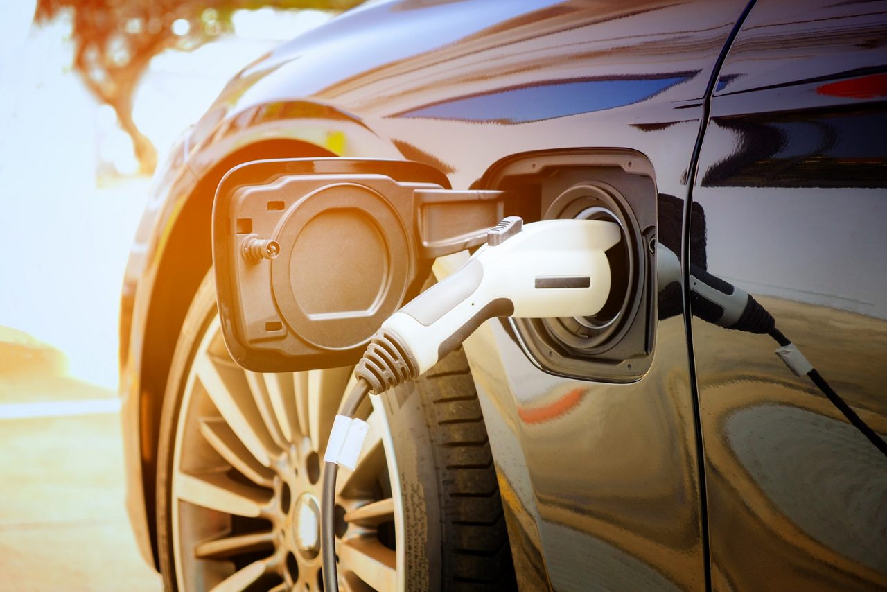 Charging modern electric car battery on the street which are the future of the Automobile, Close up of power supply plugged into an electric car being charged for hybrid . New era of vehicle fuel.