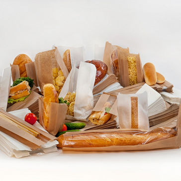 Pães e sanduíches diferentes em embalagens de papel contra um fundo branco 