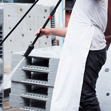 Person power washing pallets 