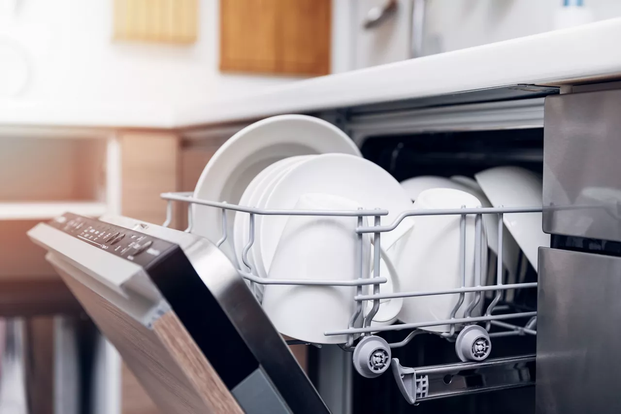 Open dishwasher with clean dishes at home kitchen