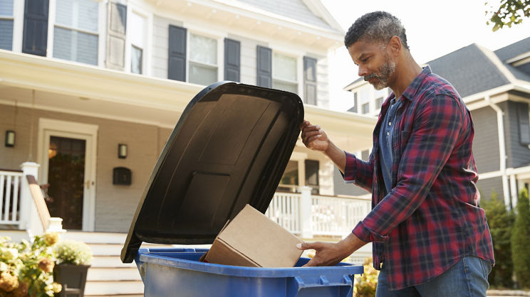 Man Filling Recycling Bin On Suburban Street