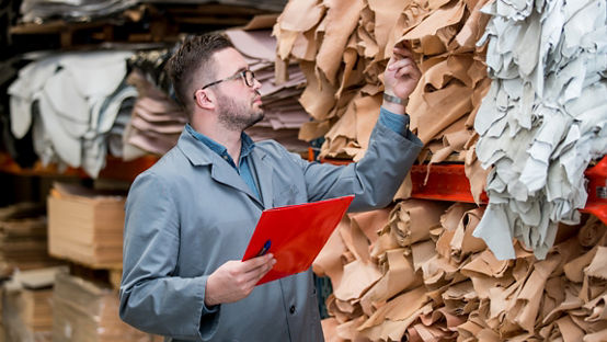 Hombre haciendo inventario en una fábrica de calzado de cuero 