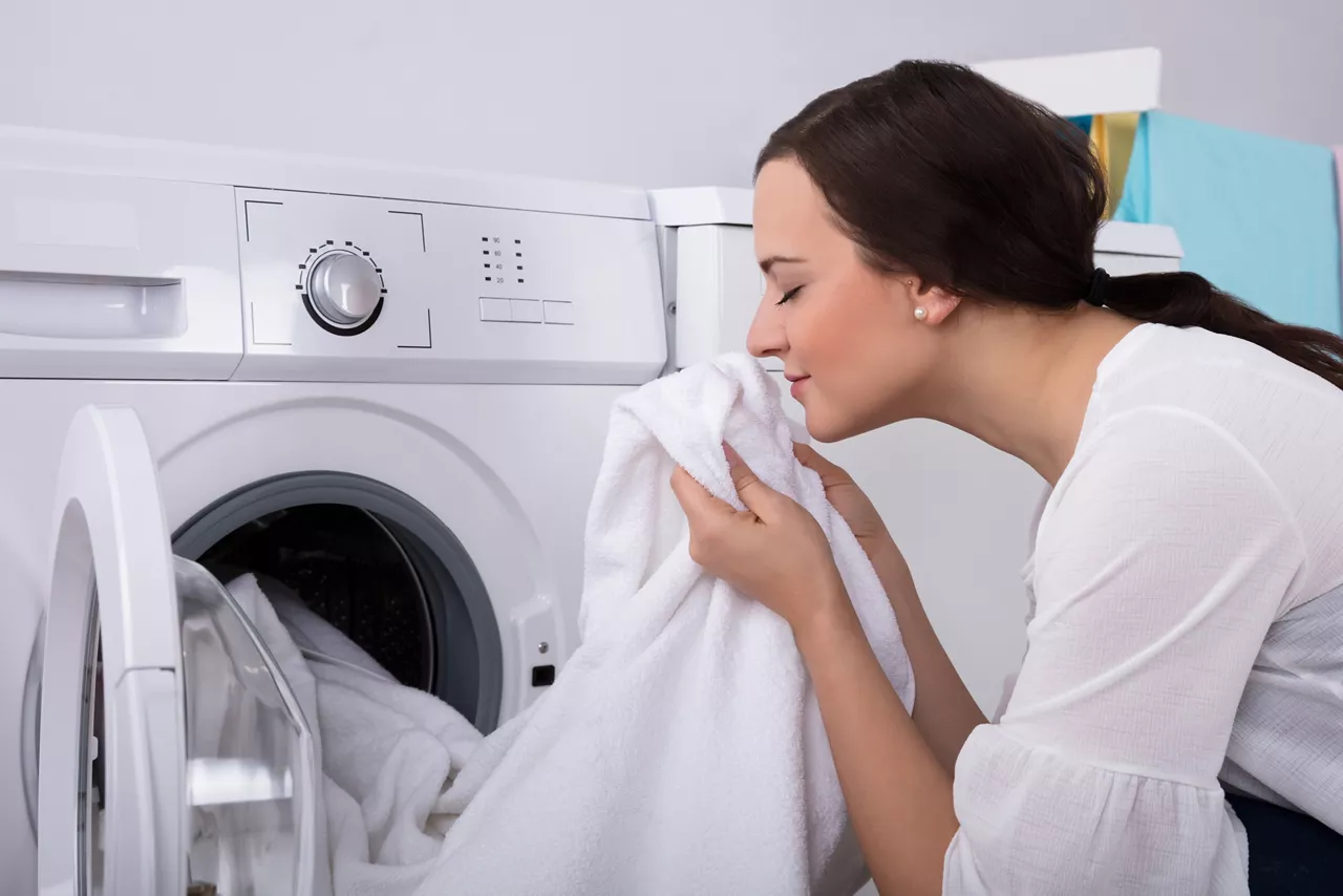 Young woman smelling fresh laundry