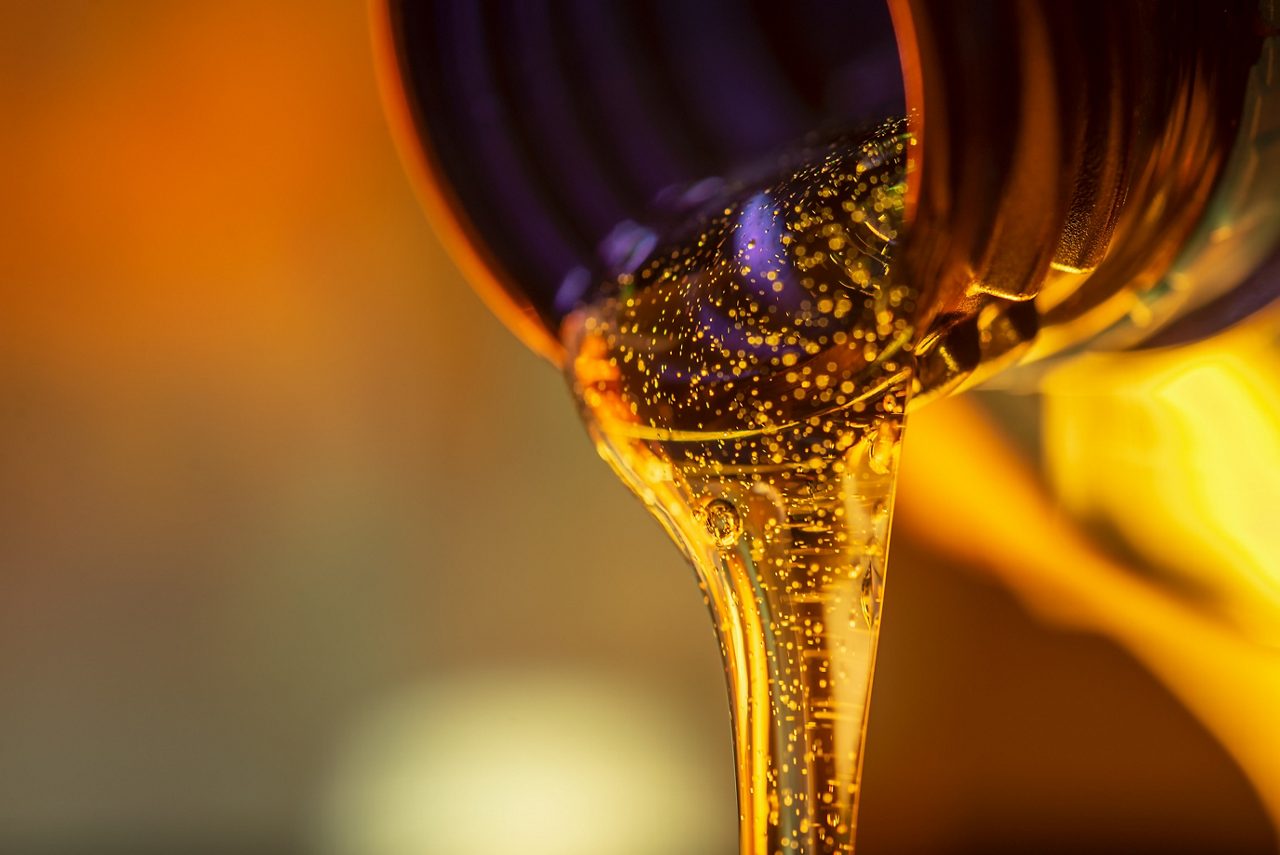 Liquid stream of motor oil flows from the neck of the bottle close-up