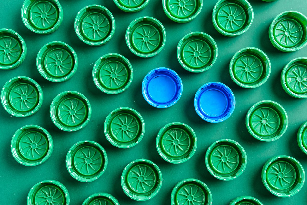 Plastic green caps from bottles and two blue caps, green caps have a design that looks like a sun.