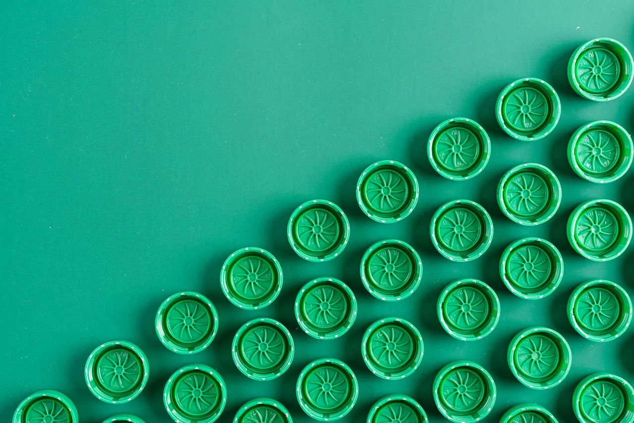 Green caps from plastic bottles folded with a repeating pattern