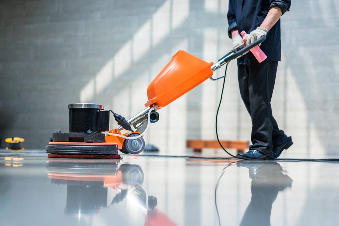 Homem limpando o chão de área comum com máquina profissional