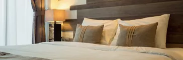 Empty double bed and lamp on side of bed in luxury in a natural style bedroom decorated with wooden boards.