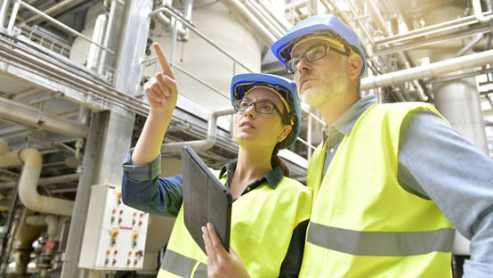 Two professionals wearing safety gear looking at test tubes