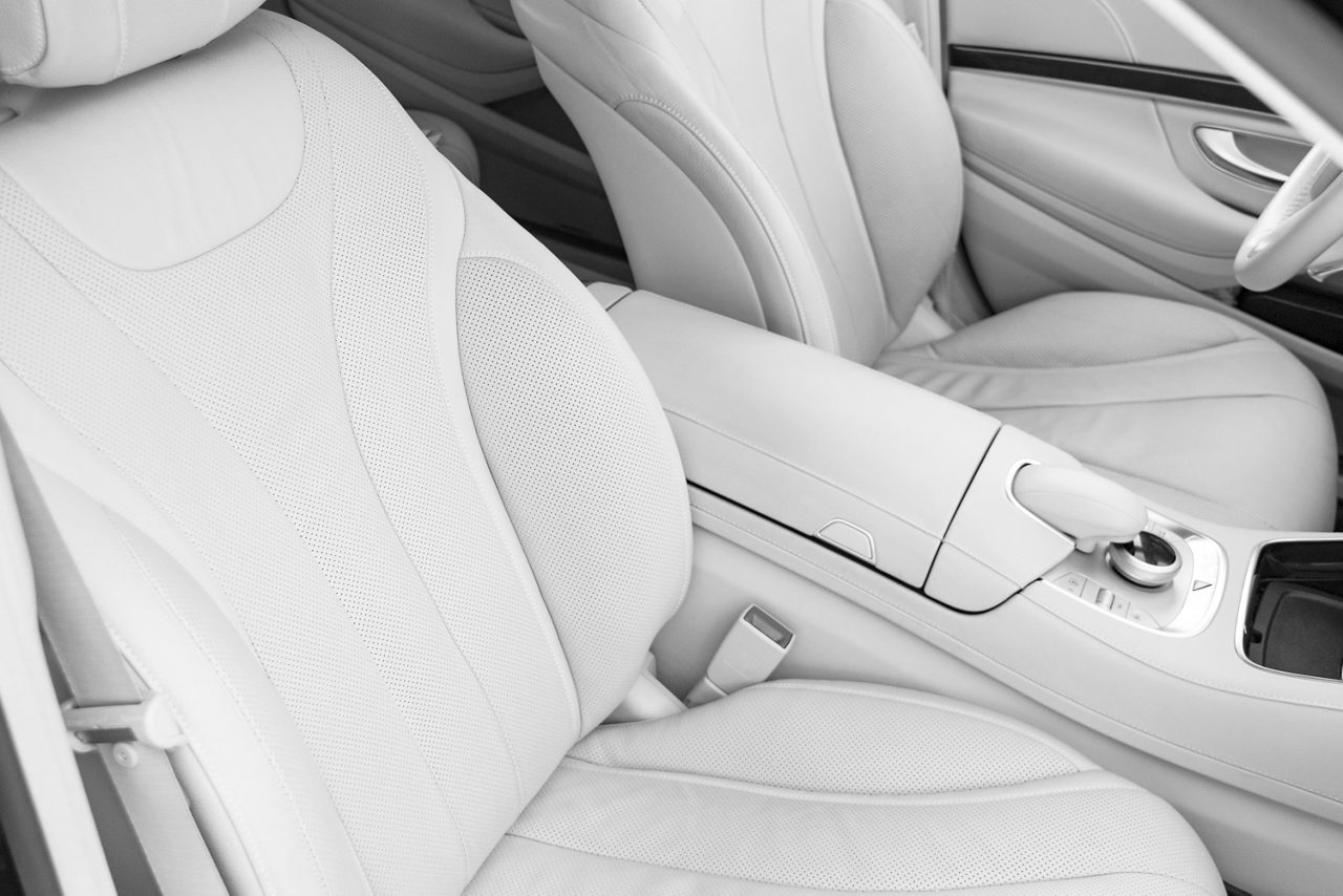 White leather interior of the luxury modern car. Leather comfortable white seats and multimedia. Steering wheel and dashboard. automatic gear stick. Car interior details. Black and white