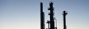 Towers at an oil and gas facility processing fossil-based fuels at sunset 