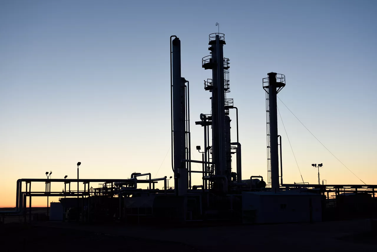 Dawn silhouette of pipes and towers at a oil and gas industry processing facility in Wyoming, USA.