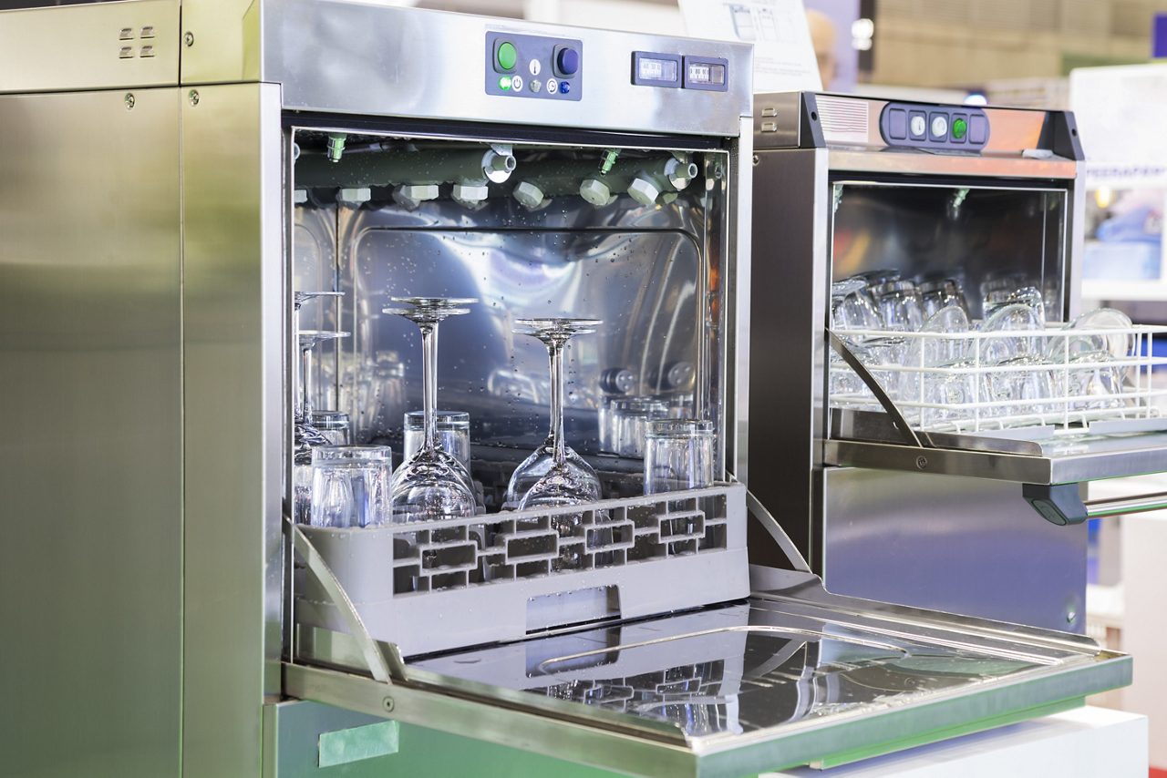 Open industrial dishwashers with clean glass, cups, plates and dishes, selective focus