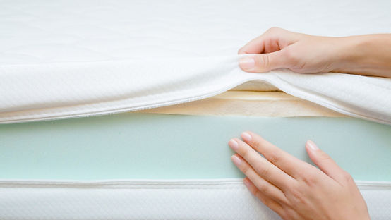 Woman's hands touching different layers of new mattress
