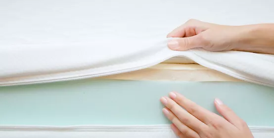 Woman's hands touching different layers of new mattress.