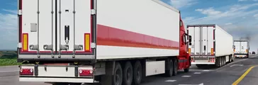 Three trucks in a line on the big highway transporting cargo loads.