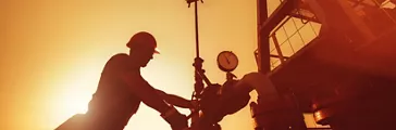 Oil worker is checking the oil pump on the sunset background 