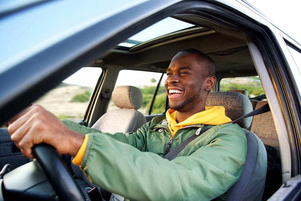 Retrato lateral de um homem feliz dirigindo um carro