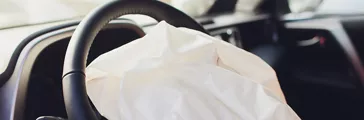 Interior of a automobile or car involved in a vehicle crash with a deployed steering column airbag