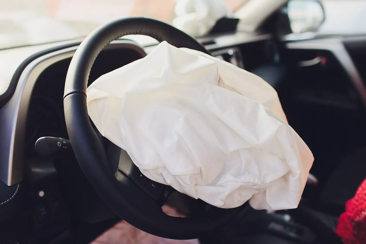 Interior of a automobile or car involved in a vehicle crash with a deployed steering column airbag