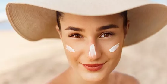 Beautiful Woman smile applying sun cream on face. 