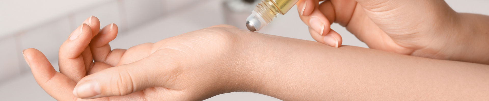 Woman applies rollerball perfume on wrist