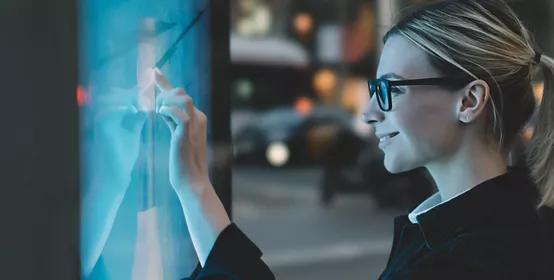 Smiling female touching a big display with advanced digital technology