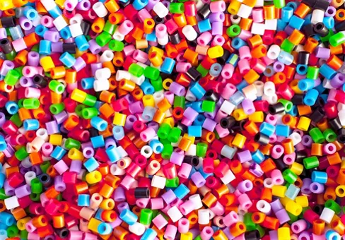 Bright colorful plastic perler beads. Abstract background.