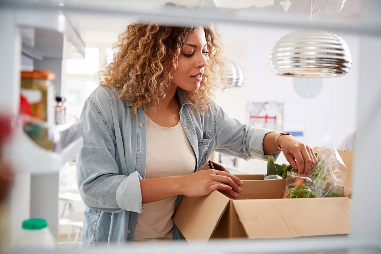 Woman unpacks online home food delivery from carboard box