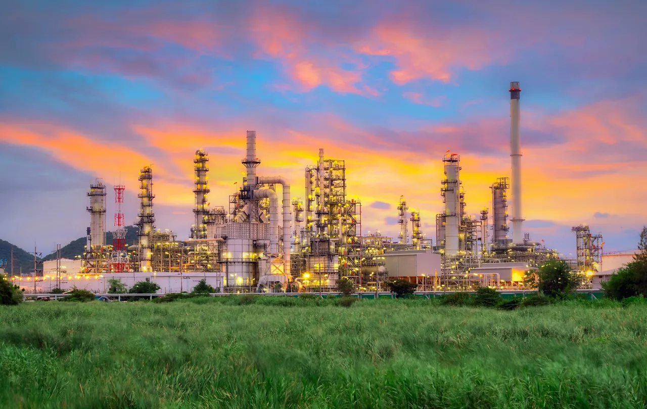 Oil and gas plant against pink and orange sky