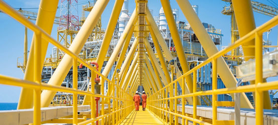 Two workers walking on the connecting bridge between quarter platform and oil and gas central processing platform, offshore oil and gas operation business.
