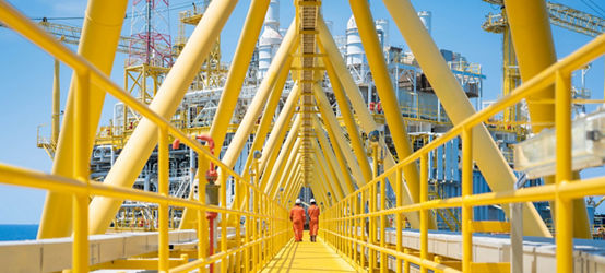 Two workers walking on the connecting bridge between quarter platform and oil and gas central processing platform, offshore oil and gas operation business.