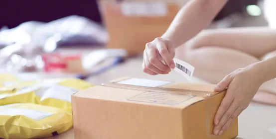 Two hands placing a shipping sticker above a box 
